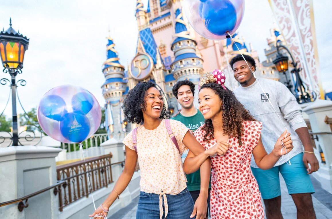 Family walking toward Cinderella Castle with colorful balloons
